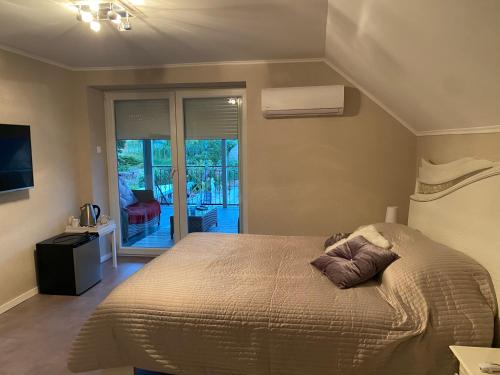 a bedroom with a large bed and a balcony at Maria Vendéghaz in Mernye