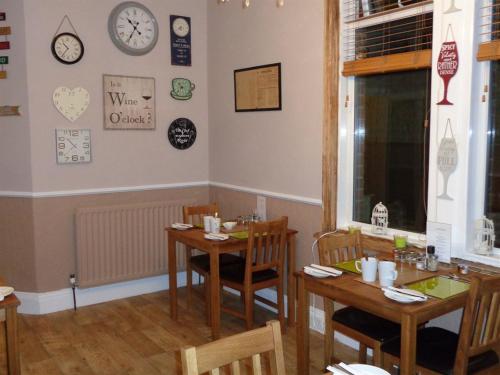 uma sala de jantar com duas mesas e um relógio na parede em Kingsmere Guest House em South Shields
