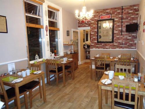 a restaurant with wooden tables and chairs in a room at Kingsmere Guest House in South Shields