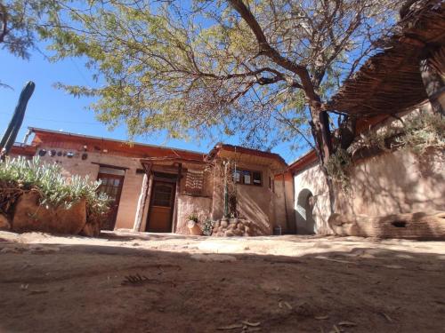an old house with a tree in front of it at Hostal Sonchek in San Pedro de Atacama