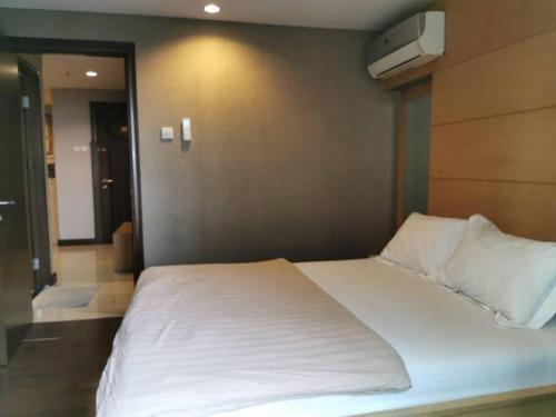 a large white bed in a room with a wall at Two Bedroom Apartment at el Royale Hotel in Bandung