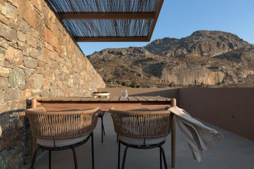 um pátio com uma mesa de madeira e 2 cadeiras em NERĒA Boutique Hotel em Plakiás