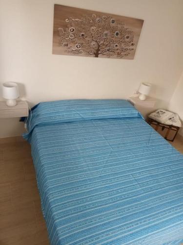 a bed with a blue comforter in a bedroom at La Fenice in Budoni