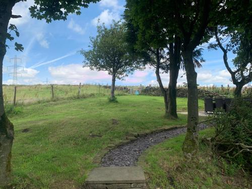 a walkway in a park with trees and a field at Luxury traditional stone farmhouse in Saddleworth in Oldham