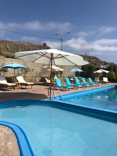 a swimming pool with chairs and umbrellas at Casuarinas Del Mar Chalet de 2 habitaciones in Canoas De Punta Sal