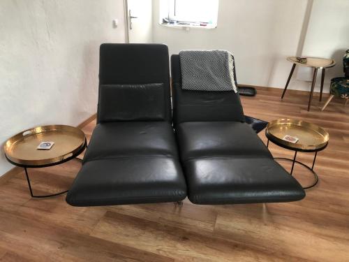 a black leather couch in a room with two tables at Ferienwohnung "Frieda" 