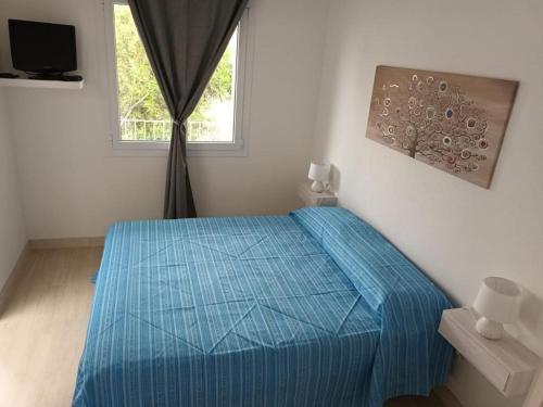 um quarto com uma cama azul e uma janela em La Fenice em Budoni