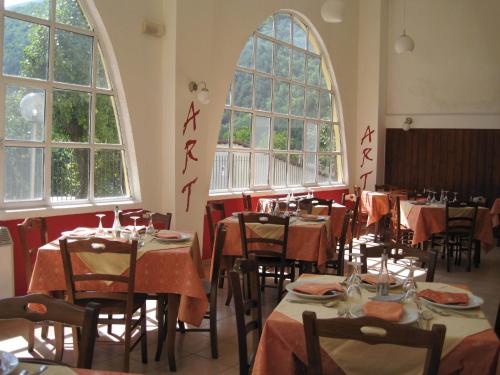 a dining room with tables and chairs and windows at Art Hotel in Villetta Barrea