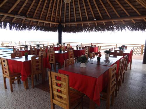 a restaurant with tables and chairs with red table cloth at Akas Hotel Apartamentos in Canoas De Punta Sal