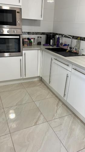 une cuisine avec des armoires blanches et un sol carrelé dans l'établissement VILLA MARCO POLO, à Cannes