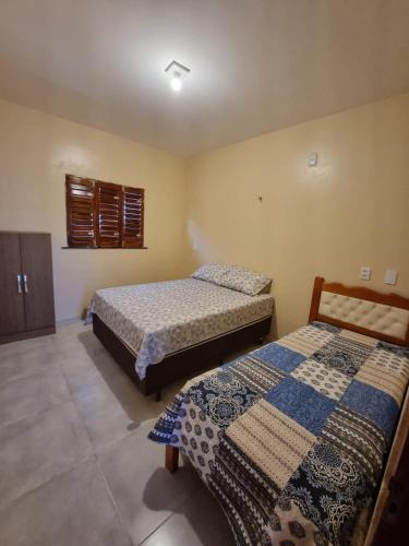 a bedroom with two beds and a window at Duplex de 2 quartos com ar condicionado , piscina e estacionamento in Aracati