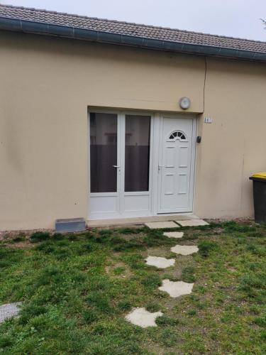 a house with a white door and a yard at Maison 3 chambres. cour Privative 2 places de parking privatives in Corquilleroy