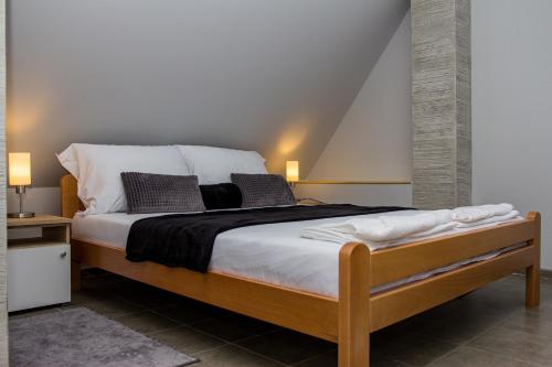 een slaapkamer met een groot bed met 2 kussens bij Feher Akac Guest House in Palić