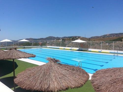 - une grande piscine avec des parasols en paille à côté dans l'établissement Apartamento Alegría, à Frigiliana