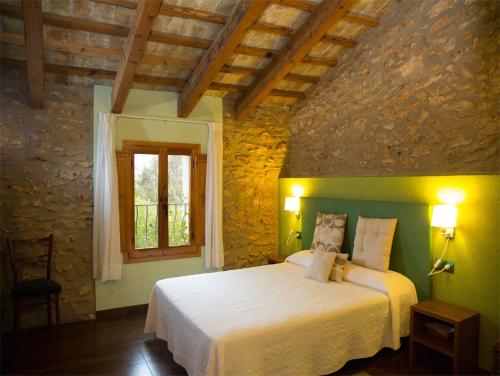 ein Schlafzimmer mit einem weißen Bett in einer Steinmauer in der Unterkunft Mas Masdeu in L'Aldea