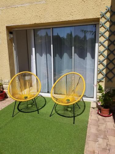 two yellow chairs sitting on the grass in front of a window at Les Lauriers in Espondeilhan