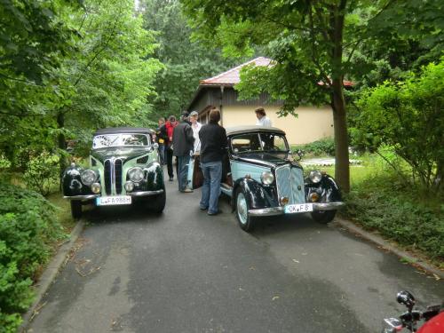 two old cars are parked on a road with people at Hotel BB Bahnhof Bertsdorf in Olbersdorf