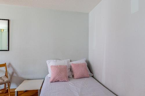 Schlafzimmer mit einem Bett mit rosa und weißen Kissen in der Unterkunft Studio Flamant - Welkeys in La Rochelle