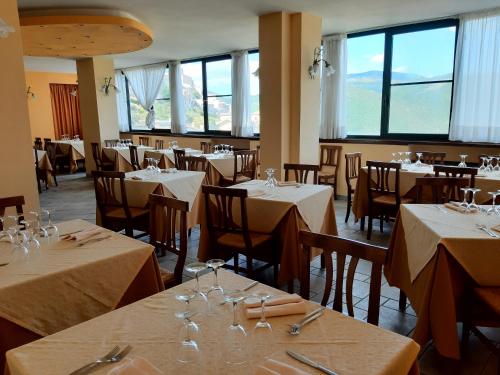 - une salle à manger avec des tables, des chaises et des fenêtres dans l'établissement Hotel Brufa, à Monteleone di Spoleto