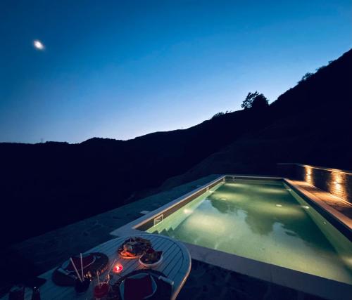 a swimming pool in the middle of a mountain at night at Colle del Faggio Nature Home in Cassego