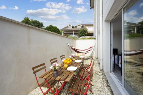 - un balcon avec une table de patio, des chaises et des fleurs dans l'établissement Appartement Canari - Bayonne - Welkeys, à Bayonne
