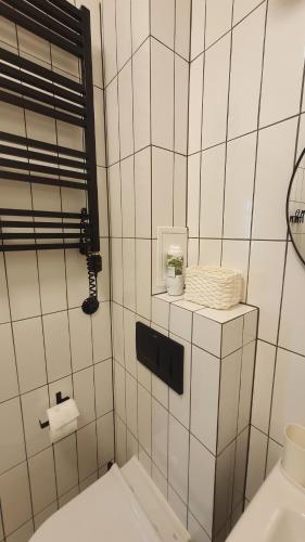 La salle de bains est pourvue de carrelage blanc, d'un lavabo et de toilettes. dans l'établissement Kurkowa Apartment, à Wrocław