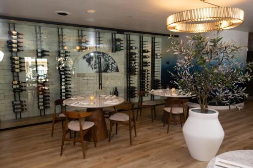 a dining room with tables and chairs and a wall of wine bottles at Toll House Hotel Los Gatos in Los Gatos