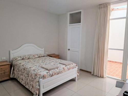 a white bedroom with a bed and a window at CASA - Mary Ann's House in Trujillo