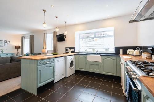 a kitchen with green cabinets and a couch at 5 bedrooms sleeps 10-12 free wifi & parking garden in Lundin Links
