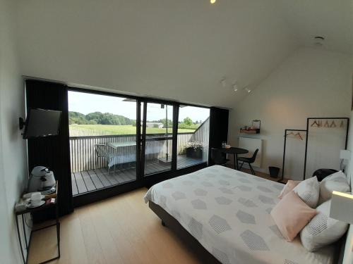 a bedroom with a large bed and a balcony at B&B De Stuifduinen in Wetteren