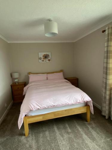 a bedroom with a bed with a pink bedspread at Four waves in Thurso