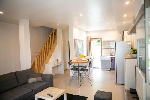 een woonkamer en een keuken met een bank en een tafel bij Appart'Hôtel L'Arbonnaise - Calme & Chic in Arbonne