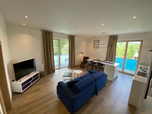 a living room with a blue couch and a tv at Apartmány Veternica v Bernarde in Nový Smokovec