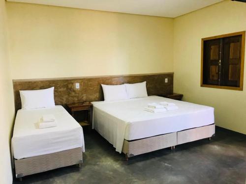 two beds in a hotel room with white sheets at Pousada Sambaíba in Palmas