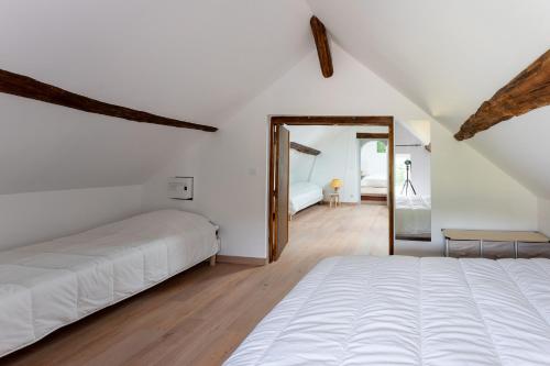 a white bedroom with a bed and a mirror at CABANA & LES PORTES DE LA FORÊT D' ORLÉANS in Nevoy