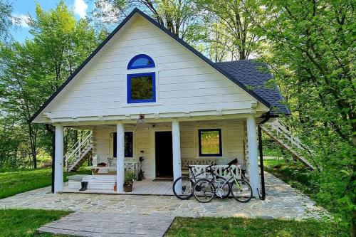 mały żółty dom z dwoma rowerami zaparkowanymi na ganku w obiekcie Biała chatka w lesie na Roztoczu w mieście Szczebrzeszyn