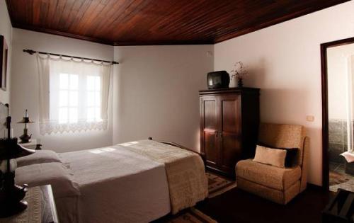 a bedroom with a bed and a chair and a window at Casa da Padaria in Piódão