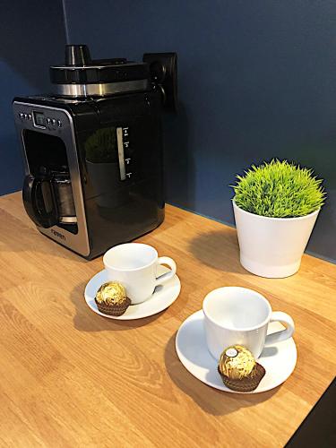 a table with two cups and two muffins and a coffee maker at Apartimento Hydral Spero in Wrocław