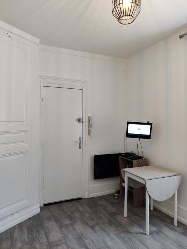 Cette chambre dispose d'une porte, d'une table et d'une télévision. dans l'établissement studio Le 46 bis, à Châlons-en-Champagne