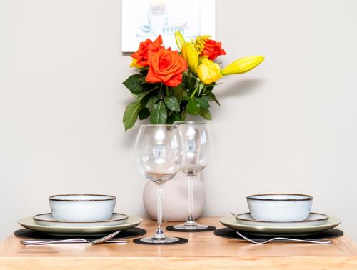 a table with plates and glasses and a vase with flowers at Byre 7 Aird of Sleat in Aird of Sleat