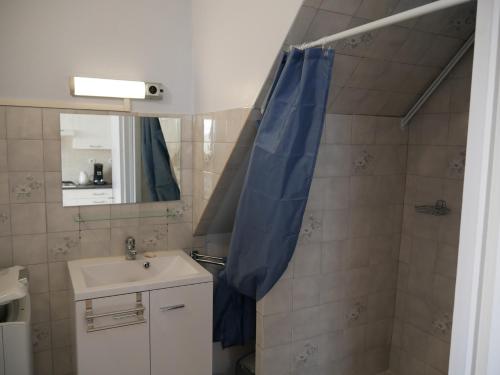 a bathroom with a sink and a blue shower curtain at CHEZ GRAND MAMIE in Polignac