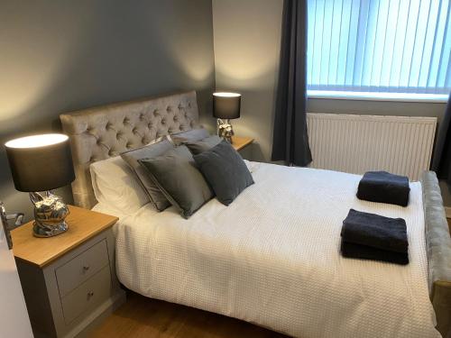 a bedroom with a bed with pillows and two lamps at Pendle House Apartment 1 in Colwyn Bay