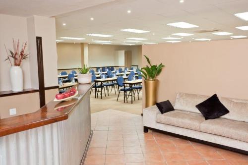 a waiting room with a couch and tables and chairs at Oudtshoorn Inn Hotel in Oudtshoorn