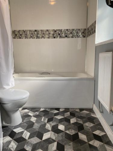un baño con inodoro y bañera en Pendle House Apartment 1, en Colwyn Bay