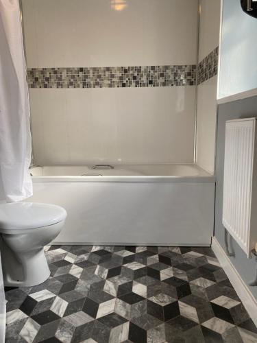 a bathroom with a toilet and a bath tub at Pendle House Apartment 1 in Colwyn Bay
