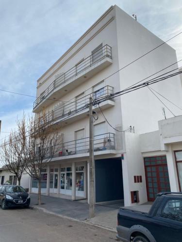 a white building with a car parked in front of it at Complejo Las Moras in Santa Rosa