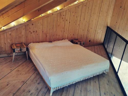 a bed in a wooden room with two tables at Domek u Gai in Klecza
