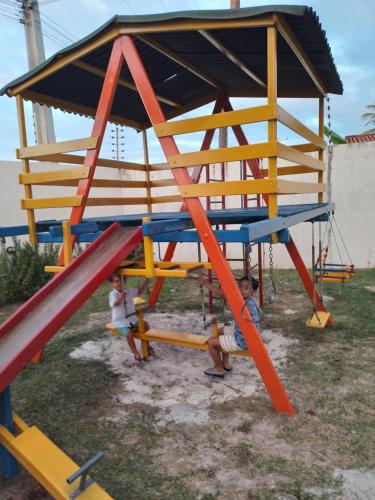 two children sitting on a play structure in a playground at Recanto Casa SOL in Barra de Jacuípe