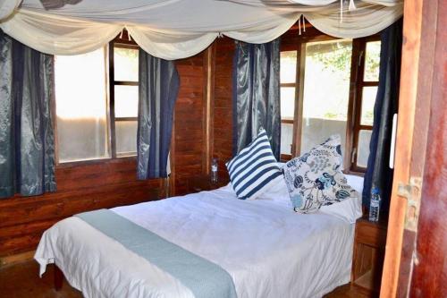 a bedroom with a white bed with pillows and windows at Mozambique,Inhambane,Barra -Entire Beach House in Inhambane