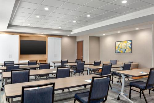 a conference room with tables and chairs and a screen at Hyatt House Bryan/College Station in College Station